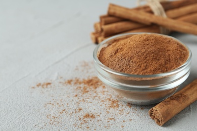 Photo of Aromatic cinnamon powder and sticks on grey table, closeup. Space for text