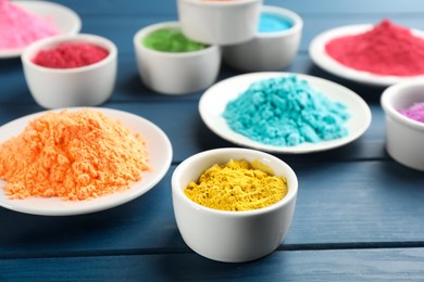 Photo of Colorful powder dyes on blue wooden background, closeup. Holi festival