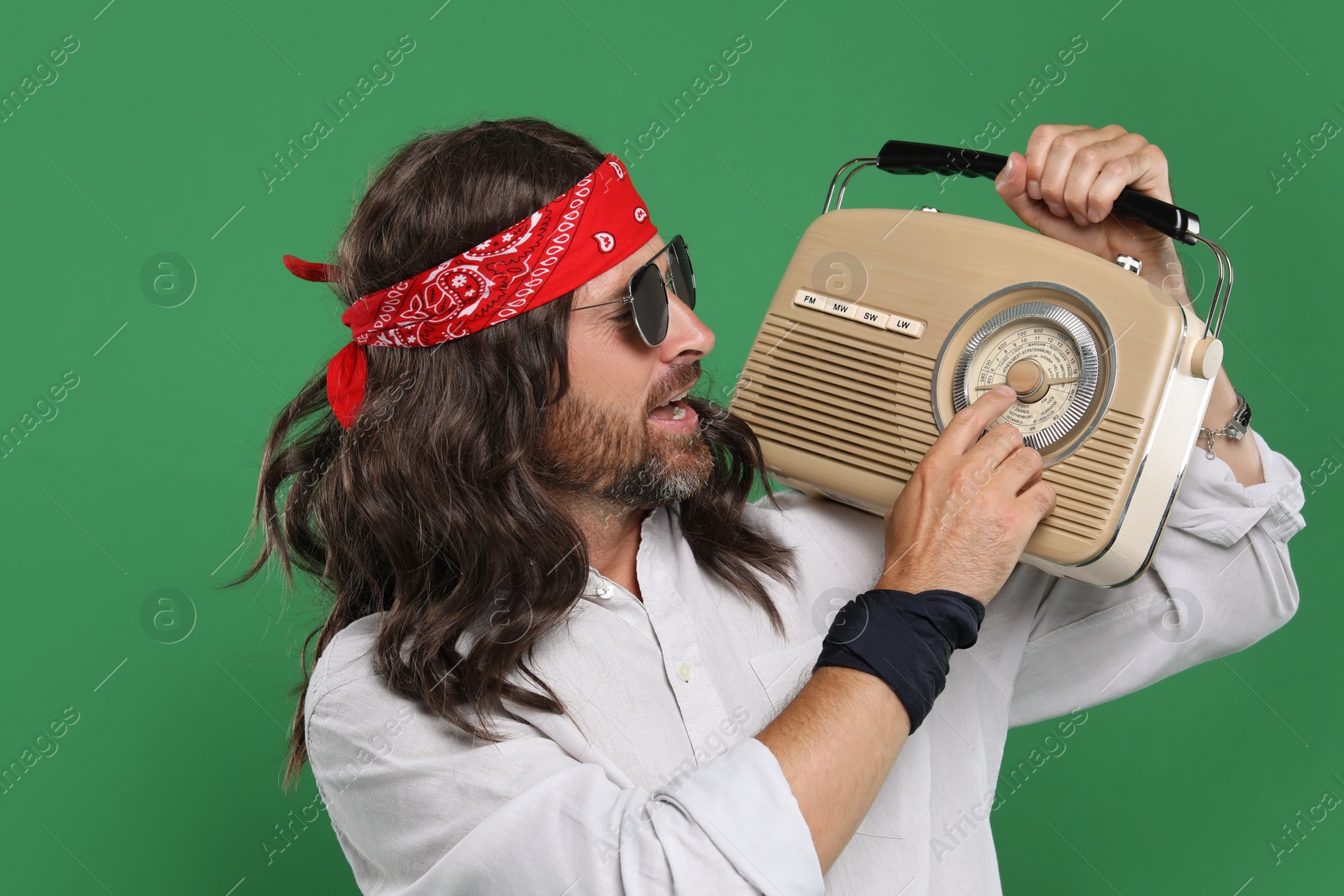 Photo of Stylish hippie man in sunglasses with retro radio receiver on green background