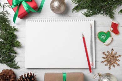 Photo of Flat lay composition with empty notebook and Christmas decorations on white wooden table, space for text. Writing letter to Santa Claus