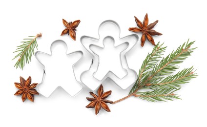 Photo of Gingerbread man cookie cutters, fir branches and anise stars on white background, top view