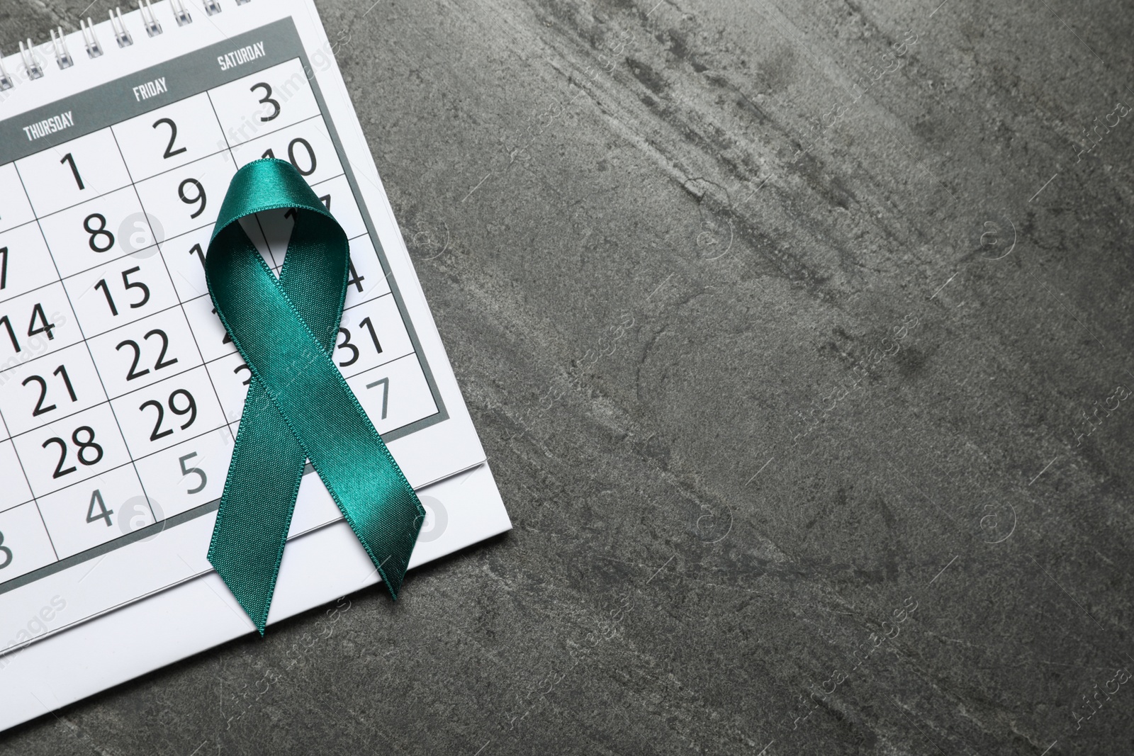 Photo of Flat lay composition with teal ribbon and calendar on grey background. Space for text