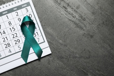 Flat lay composition with teal ribbon and calendar on grey background. Space for text