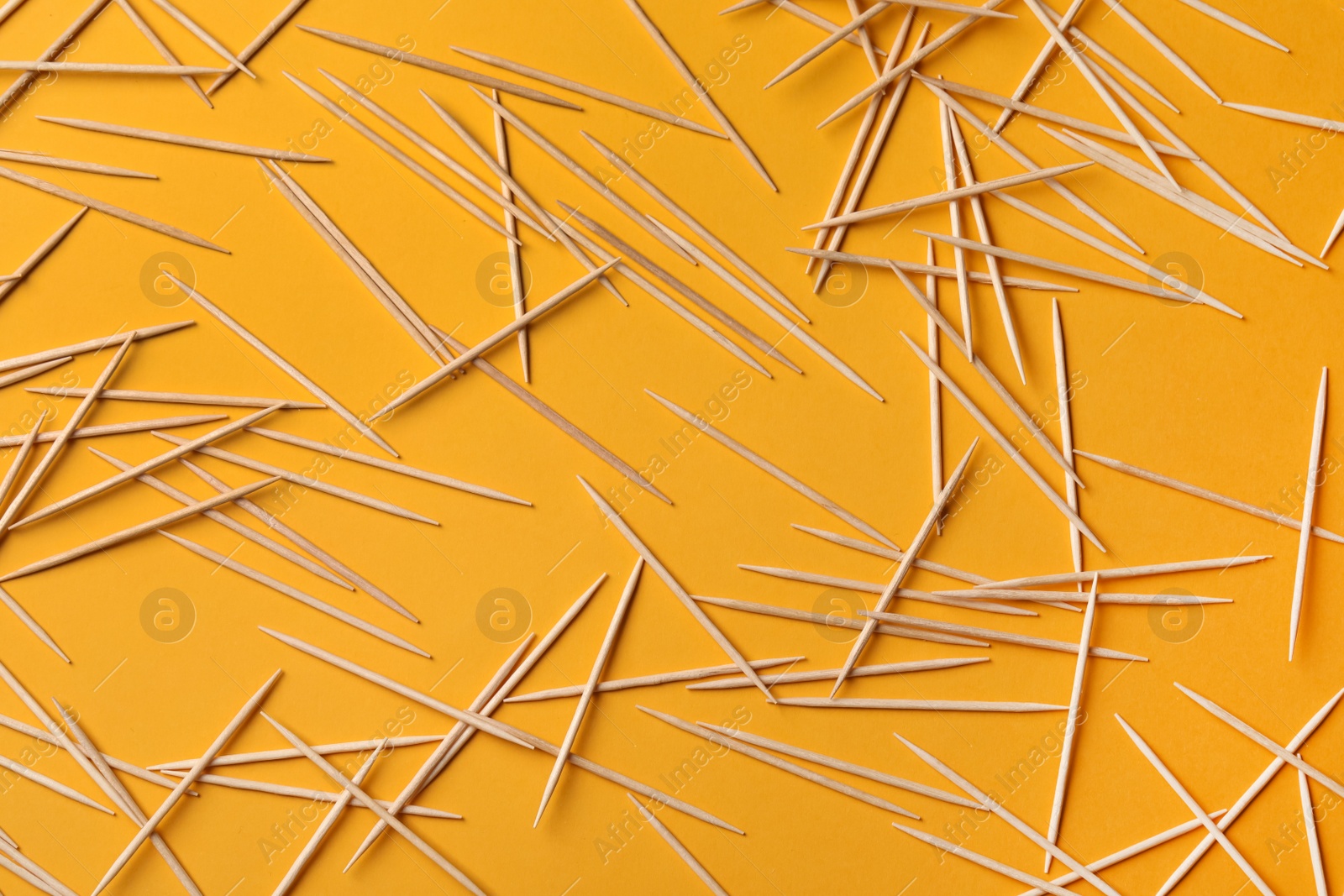 Photo of Wooden toothpicks on orange background, flat lay