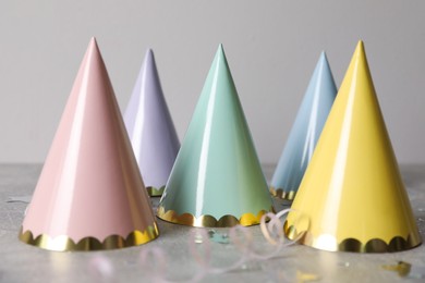 Birthday party hats, serpentine streamers and confetti on grey table