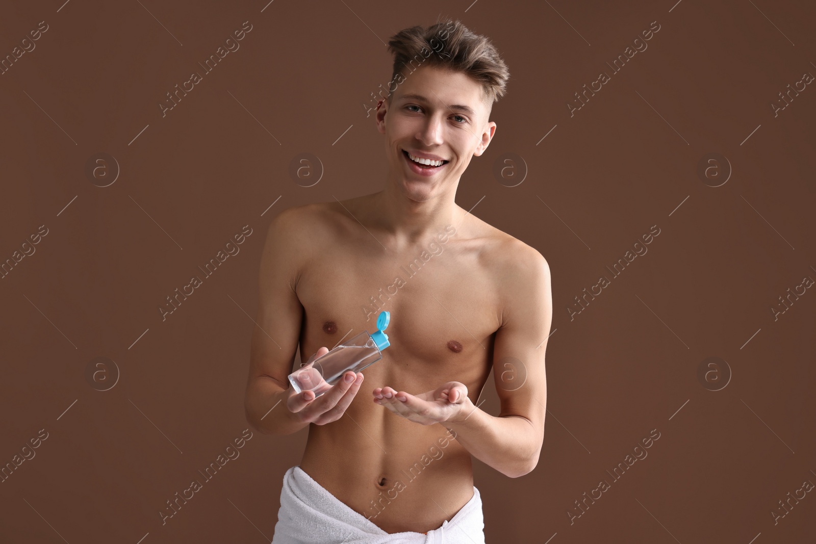 Photo of Handsome man with body lotion on brown background