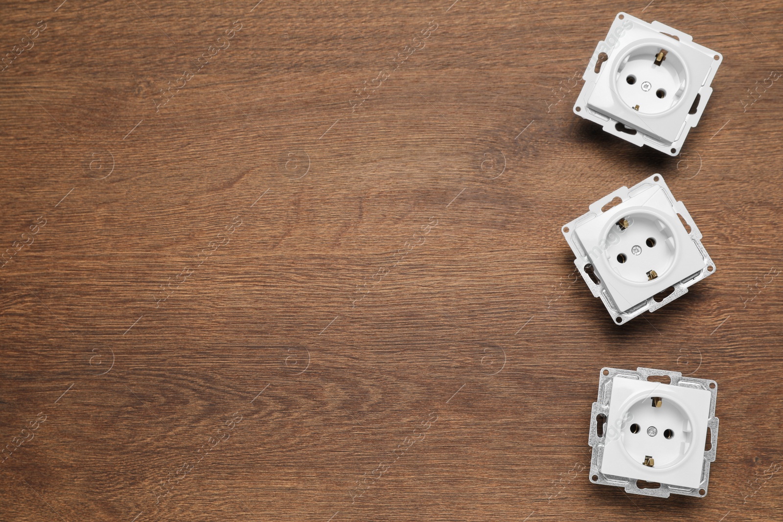 Photo of Power sockets on wooden table, flat lay. Space for text