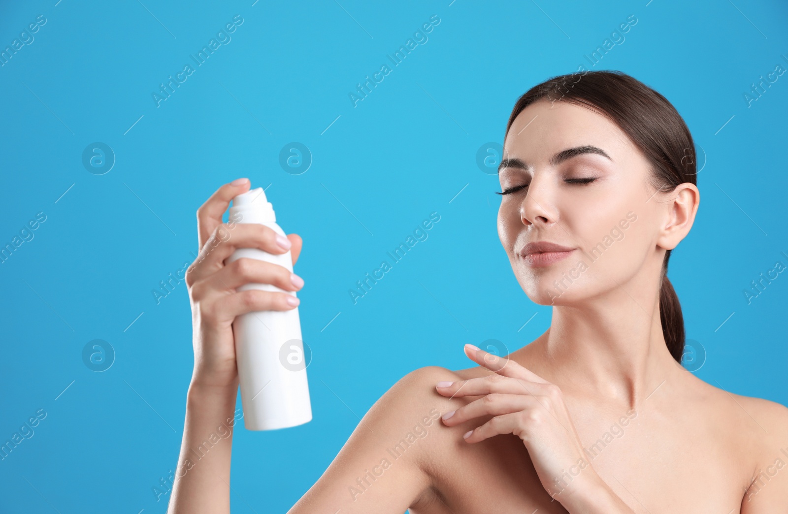 Photo of Young woman with bottle of thermal water on color background. Cosmetic product