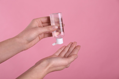 Photo of Woman applying antiseptic gel on pink background, closeup