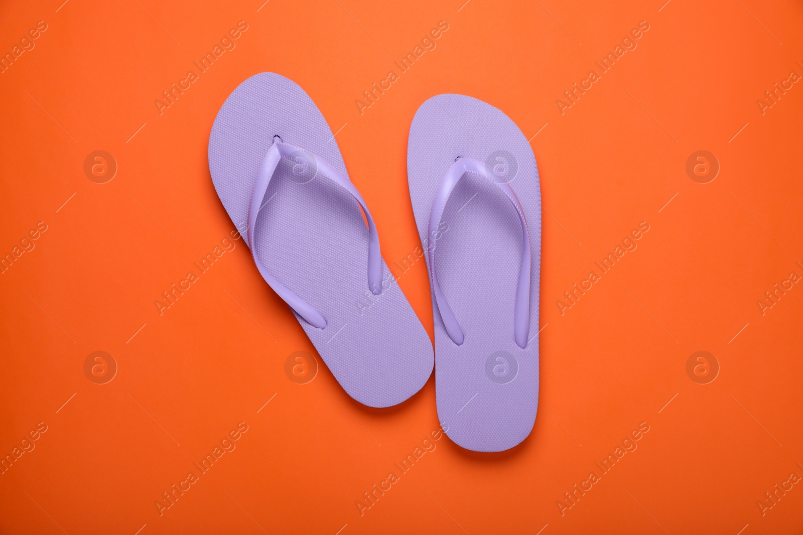 Photo of Stylish violet flip flops on orange background, top view