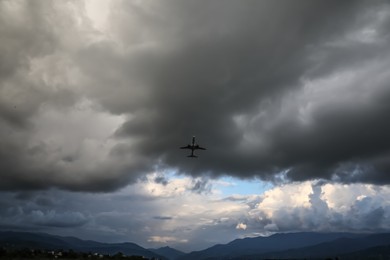 Photo of Modern white airplane flying in sky with clouds, low angle view