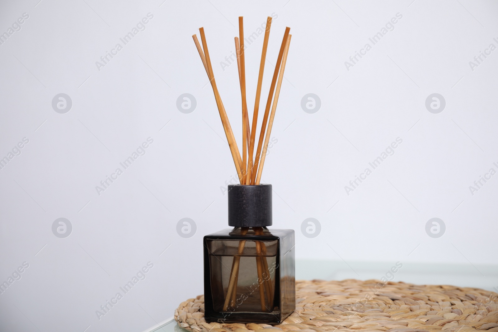 Photo of Aromatic reed freshener on table near white wall