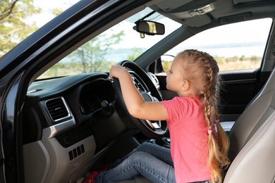 Photo of Little girl playing with steering wheel in car. Family trip