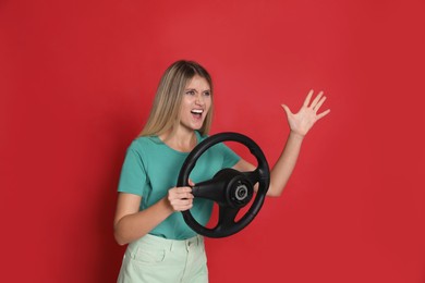 Photo of Emotional young woman with steering wheel on red background