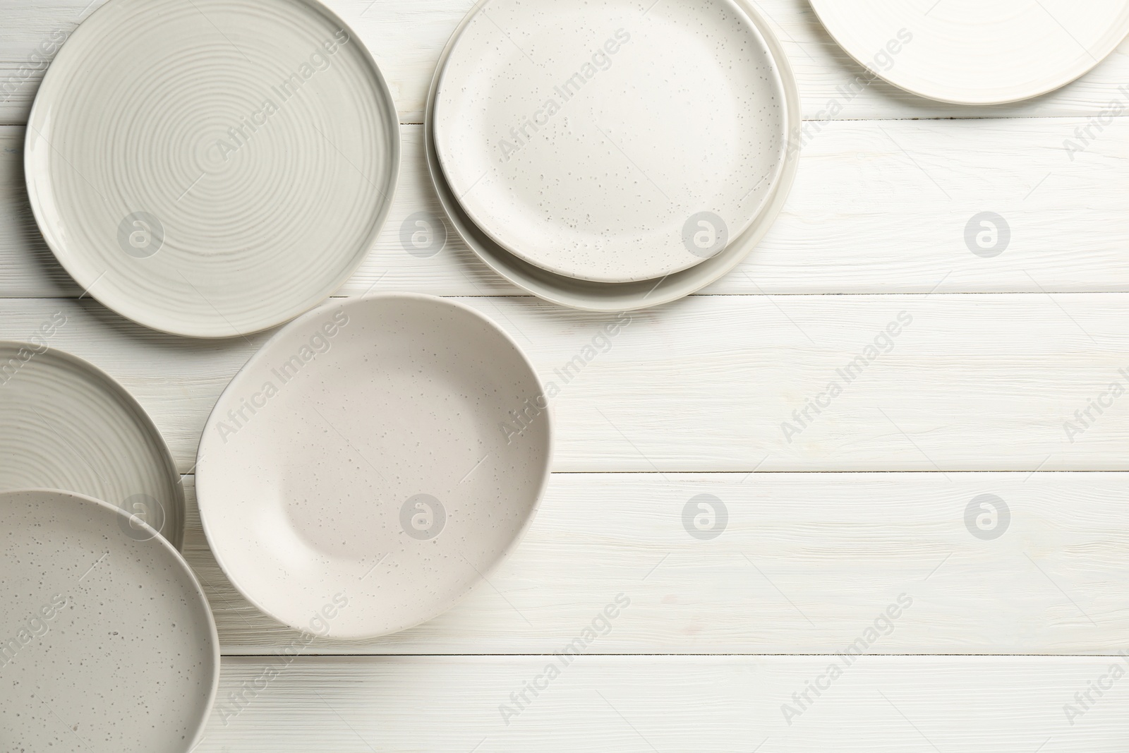 Photo of Beautiful ceramic plates on white wooden table, flat lay