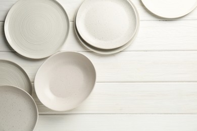 Photo of Beautiful ceramic plates on white wooden table, flat lay