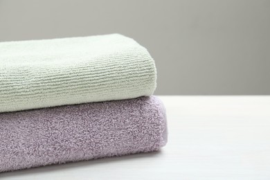 Photo of Different folded towels on white wooden table, closeup. Space for text