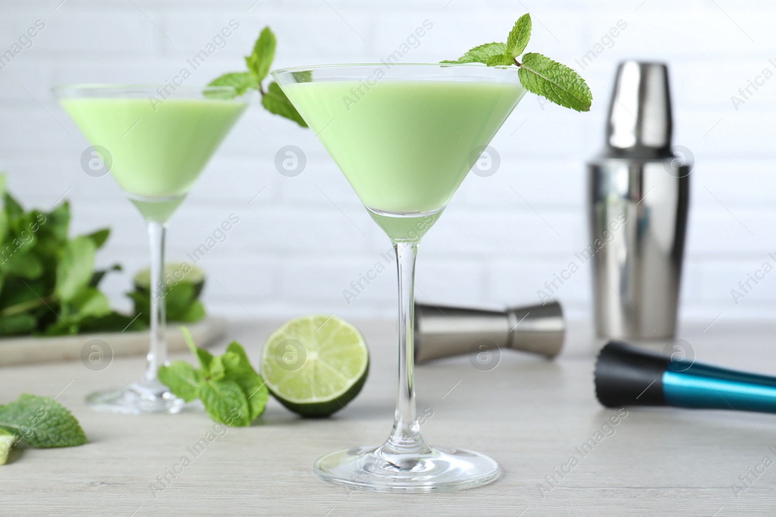 Photo of Delicious mint liqueur with green leaves on white wooden table