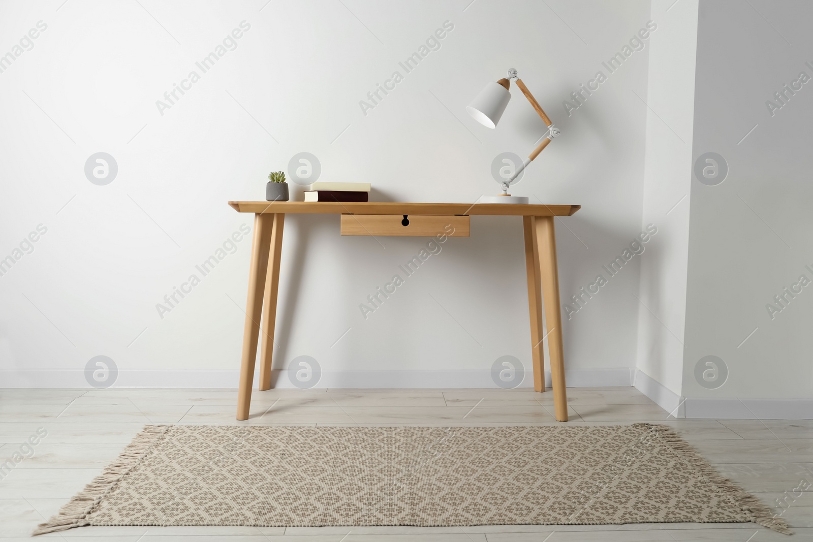 Photo of Stylish lamp, books and houseplant on wooden table in light room. Interior design