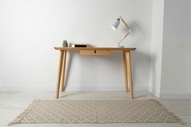 Stylish lamp, books and houseplant on wooden table in light room. Interior design