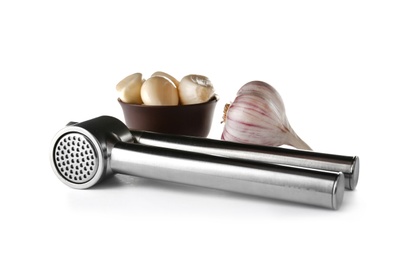 Photo of Garlic press and bowl with cloves on white background