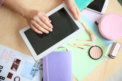 Female beauty blogger with tablet at table, top view