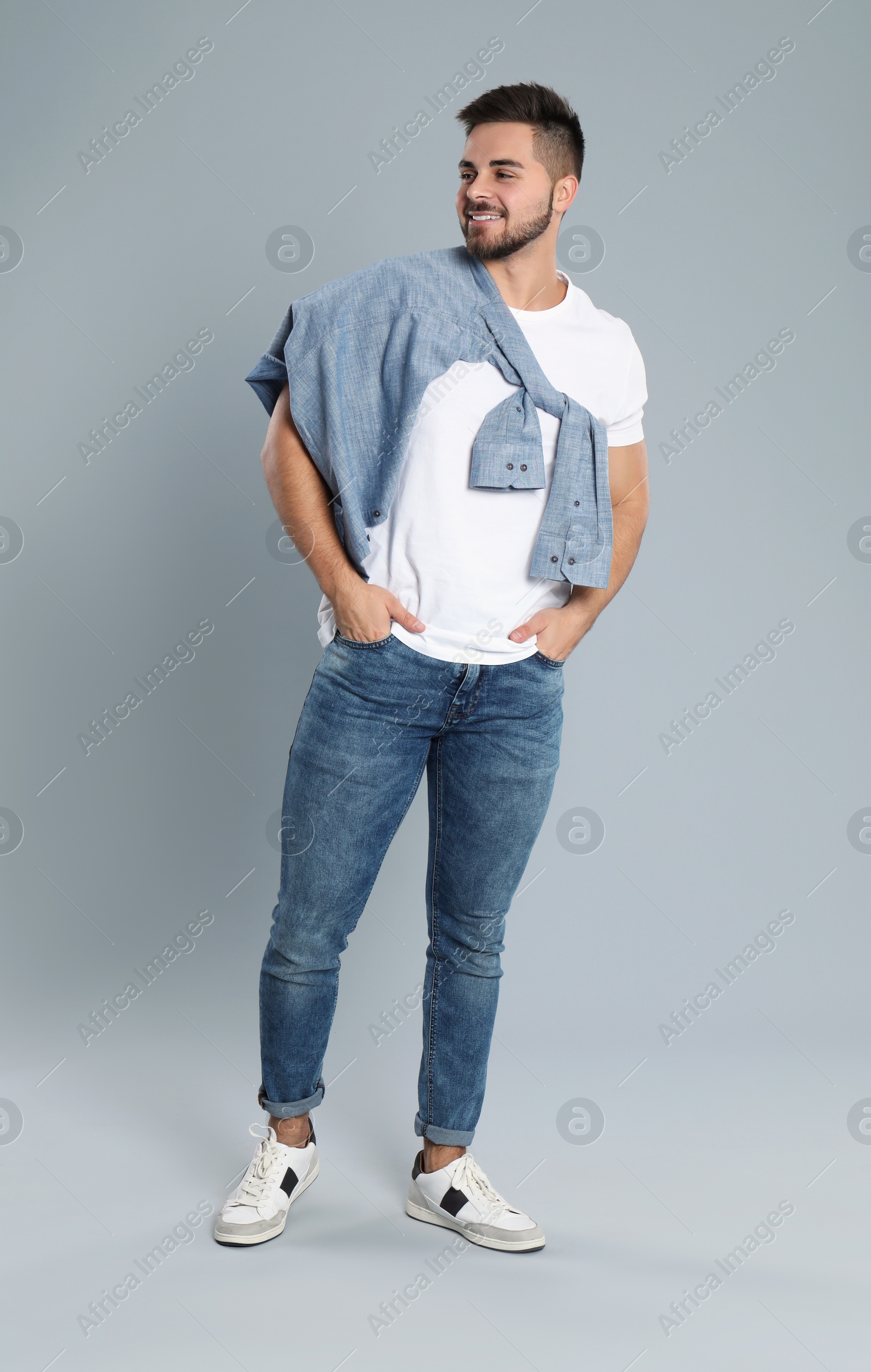 Photo of Young man in stylish jeans on grey background