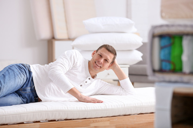 Photo of Man testing soft mattress in furniture store