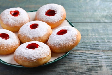 Photo of Hanukkah doughnuts with jelly and sugar powder served on wooden table, closeup