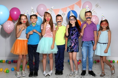 Photo of Happy children with photo booth props at birthday party indoors