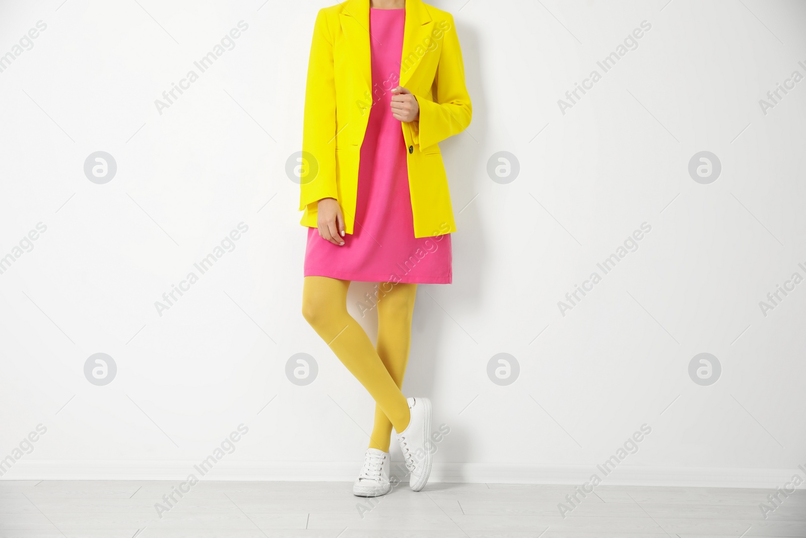 Photo of Woman wearing yellow tights near white wall, closeup