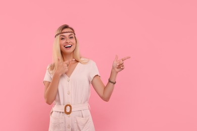Photo of Portrait of happy hippie woman pointing at something on pink background. Space for text