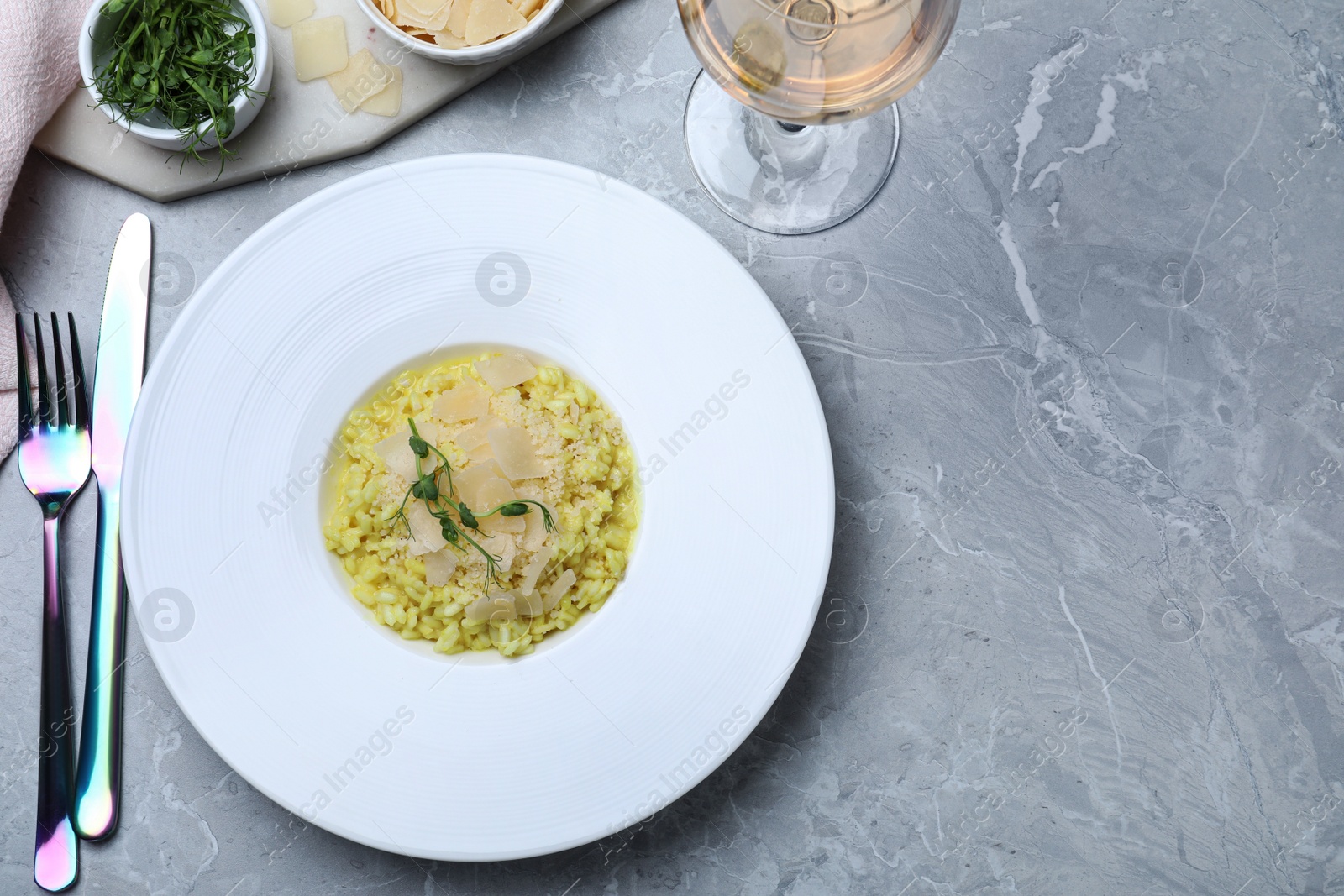 Photo of Delicious risotto with cheese on grey marble table, flat lay. Space for text