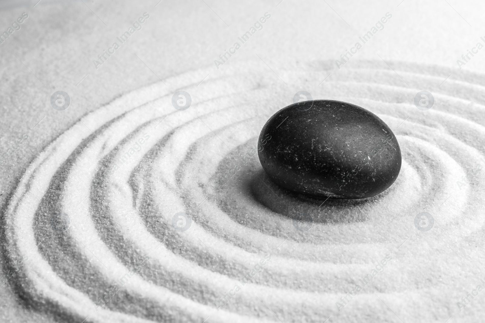 Photo of Black stone on sand with pattern. Zen, meditation, harmony