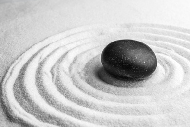 Photo of Black stone on sand with pattern. Zen, meditation, harmony