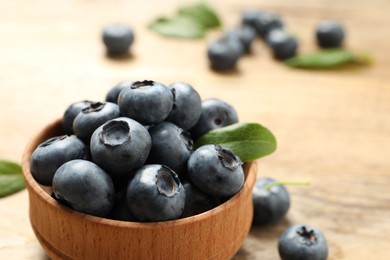 Photo of Bowl of tasty fresh blueberries on wooden table, closeup. Space for text