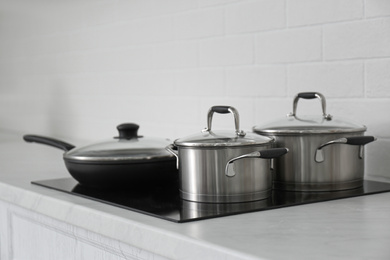 Saucepots and frying pan on induction stove in kitchen