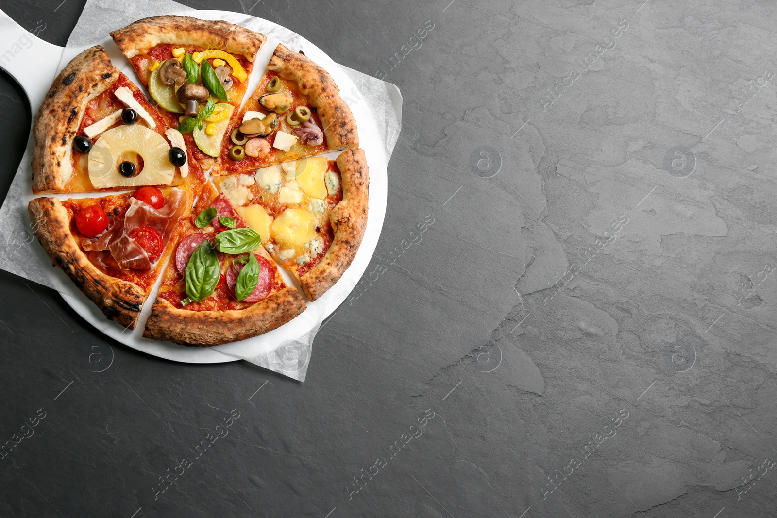 Photo of Slices of different pizzas on grey table, top view. Space for text