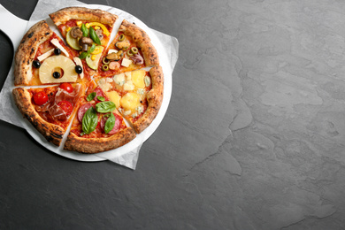Photo of Slices of different pizzas on grey table, top view. Space for text