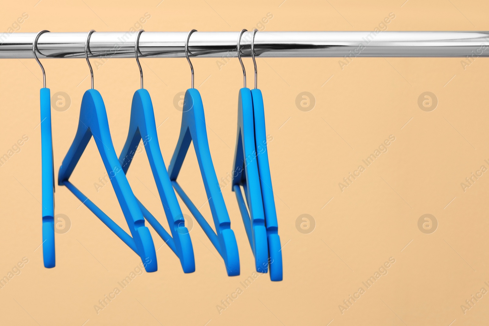 Photo of Clothes hangers on metal rail against color background