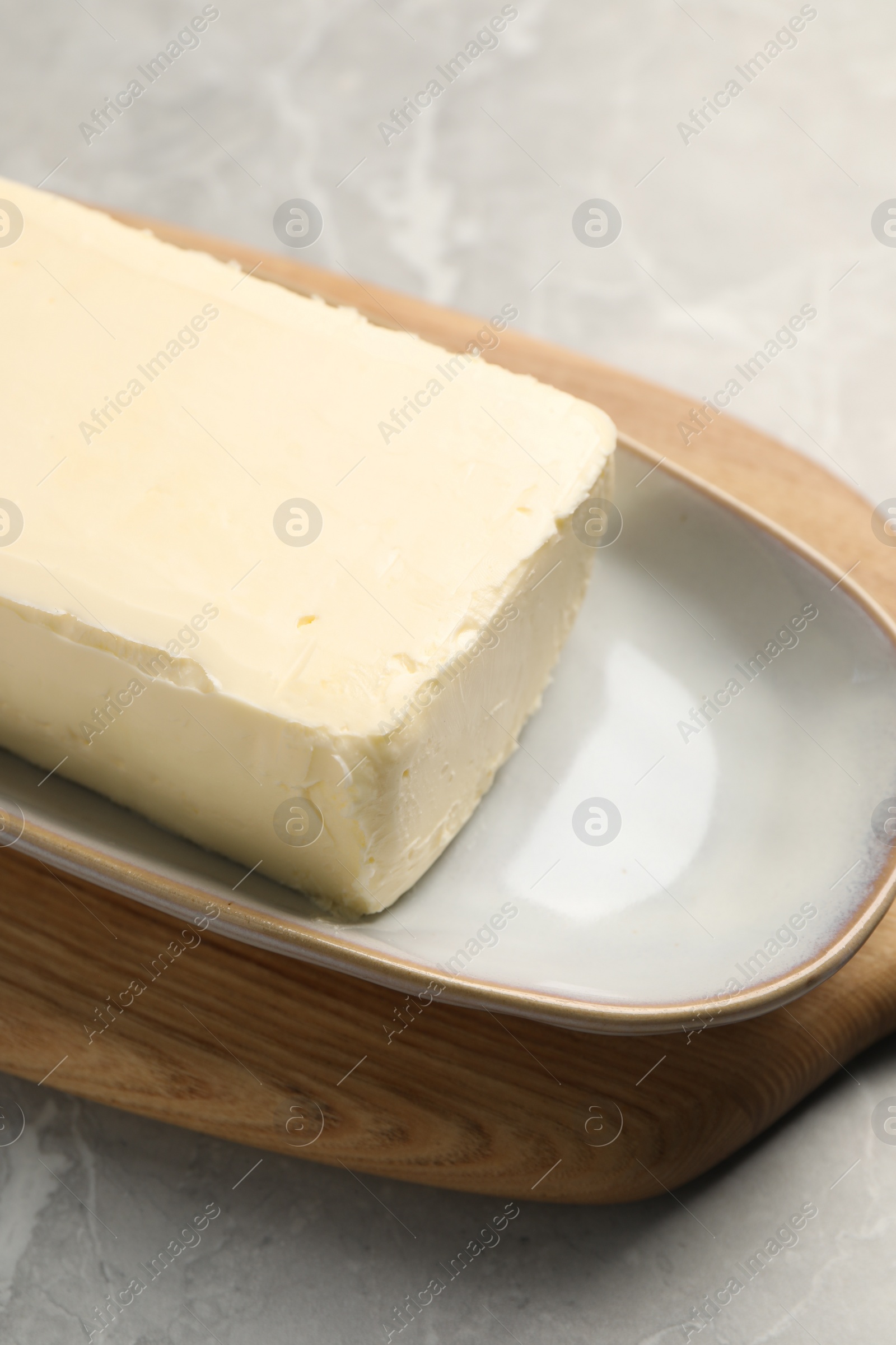 Photo of Block of tasty butter on grey table, closeup