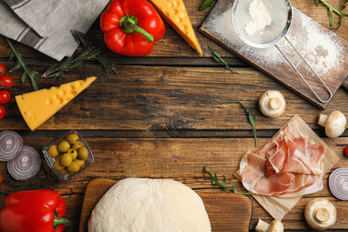 Photo of Flat lay composition with dough and fresh ingredients on wooden table, space for text. Pizza recipe