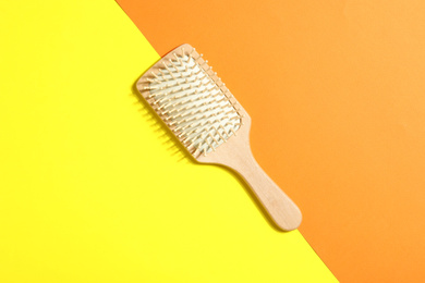 Wooden hair brush on color background, top view