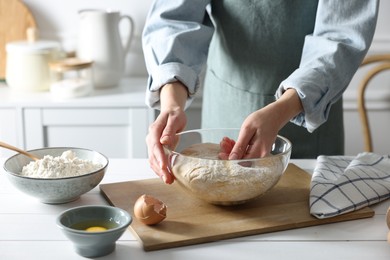 Woman kneading dough at white wooden table in kitchen, closeup