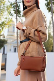 Photo of Fashionable young woman with stylish bag on city street, closeup