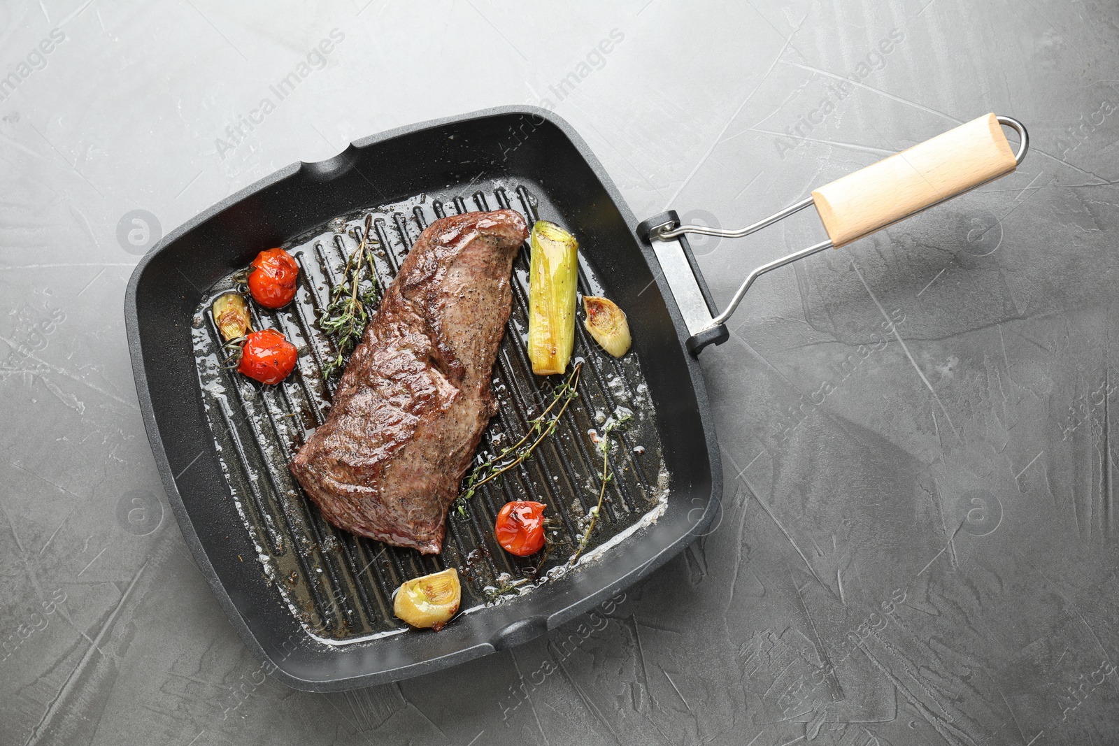 Photo of Delicious grilled beef meat and vegetables in pan on grey table, top view