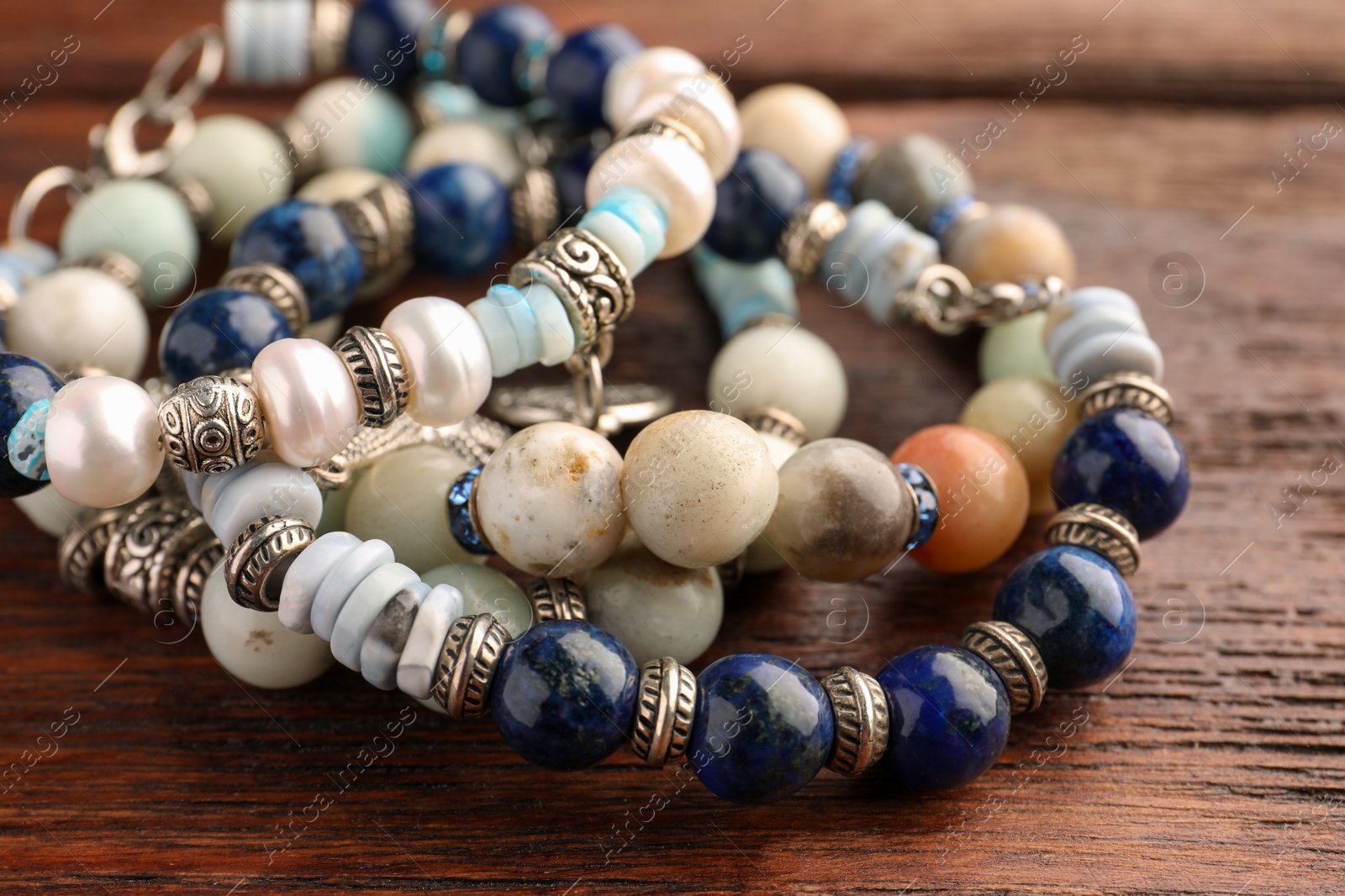 Photo of Beautiful bracelets with gemstones on wooden table, closeup