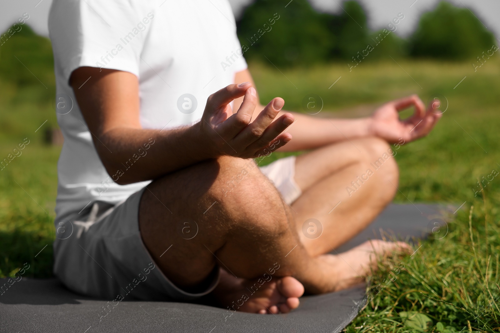 Photo of Man practicing yoga on mat outdoors, closeup. Lotus pose