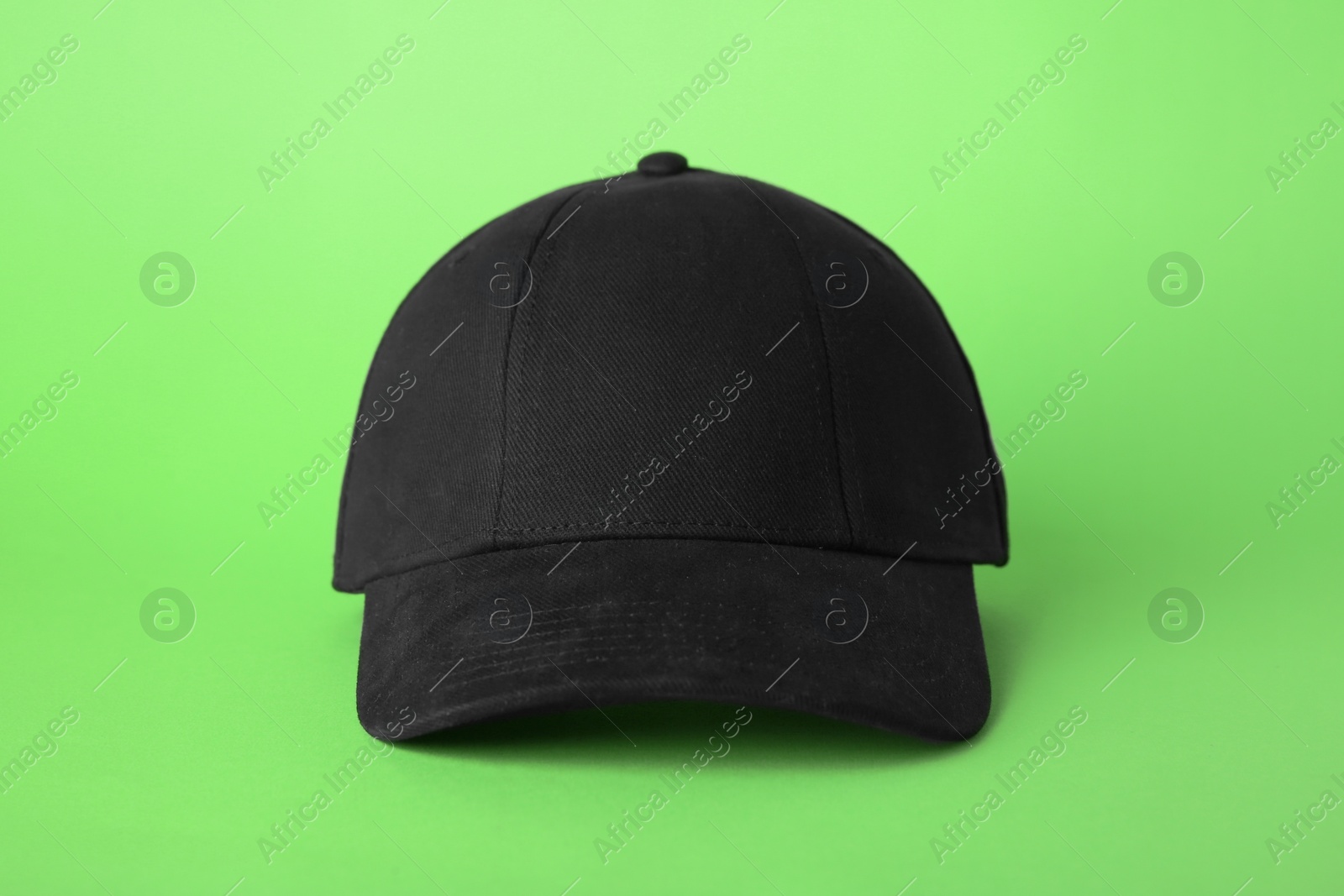 Photo of Stylish black baseball cap on light green background