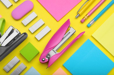 Photo of Flat lay composition with new staplers on yellow background